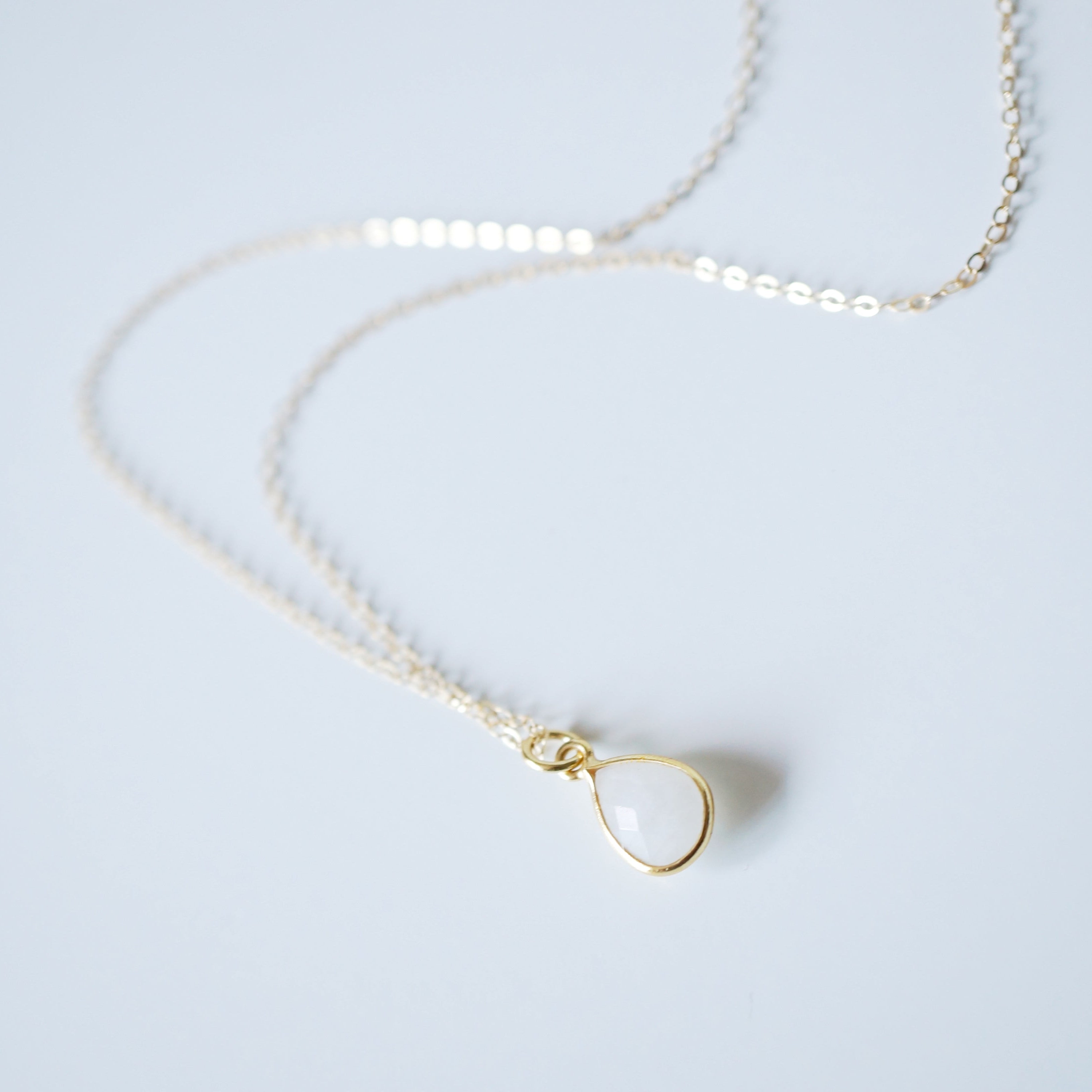 Gold necklace with a small pendant on a light gray background